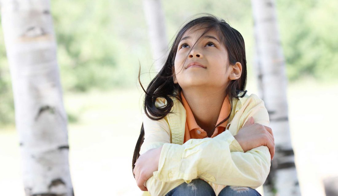 girl outside sitting under trees